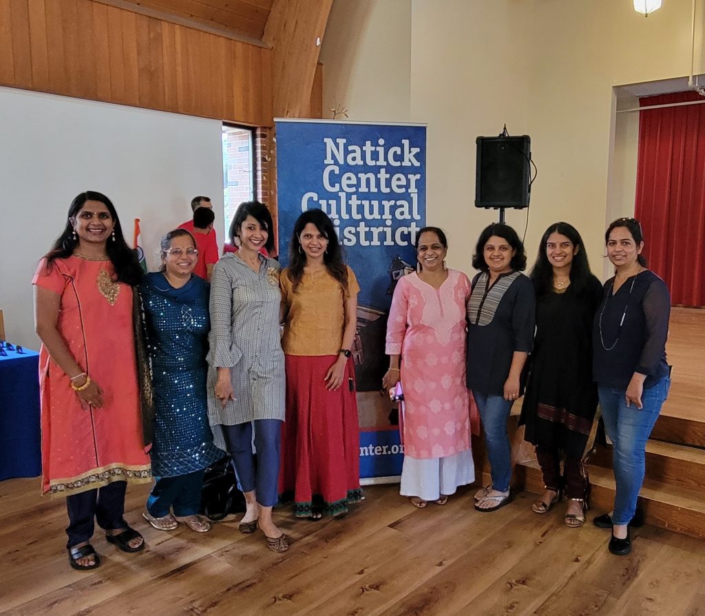 Eight women standing in front of a Blue Natick Center Cultural District, inside the Spiritual Center