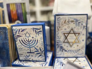 A modern color photograph of two box sets of cards. Both are blue, the one on the right has a gold star of David, the one on the left has a menorah.