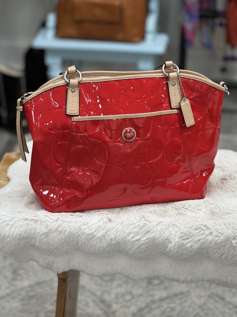 Modern color photograph of a red patent leather purse with brown details.