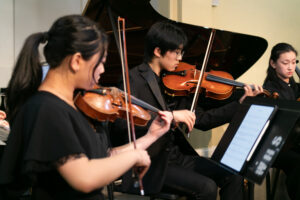 Students play string instruments during a concert.